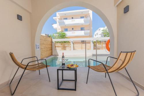卡尔扎迈纳Cabana Blu Hotel & Suites的带2把椅子和桌子的房间以及游泳池