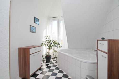 诺登Pension Altes Zollhaus的浴室设有白色浴缸和黑白格子地板。