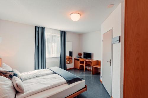 卢特巴赫Hotel Rössli Luterbach的配有一张床和一张书桌的酒店客房