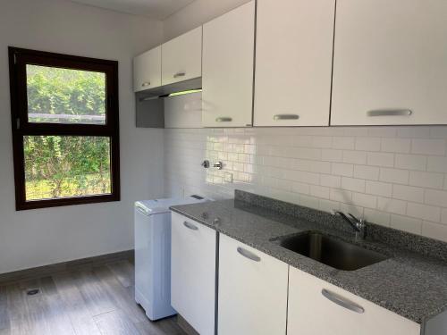 萨尔塔Acogedora y amplia casa en Salta!的厨房配有白色橱柜、水槽和窗户。