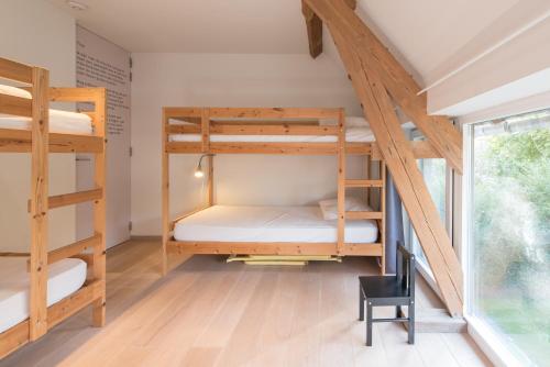 Lo-ReningeHet Wagenhuis的带三张双层床和椅子的房间