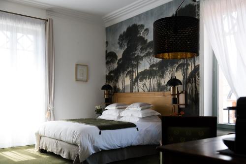 BoënLe Passagran的卧室配有一张床,墙上挂有绘画作品