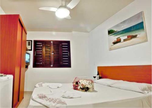 纳塔尔倍加弗洛尔旅馆的卧室配有一张白色大床和木制床头板