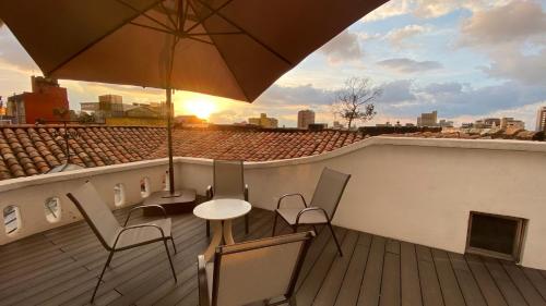 波哥大REPUBLICANA CASA HOSTAL - HABITACION 5 TAIRONA的阳台配有桌椅和遮阳伞。