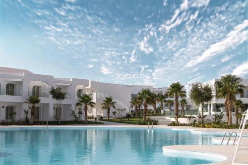 沙姆沙伊赫Meraki Resort Sharm El Sheikh Adults only的棕榈树建筑前的大型游泳池