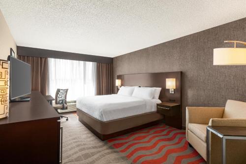 萨默维尔Holiday Inn Boston Bunker Hill Area, an IHG Hotel的酒店客房配有一张床、一张桌子和一把椅子。