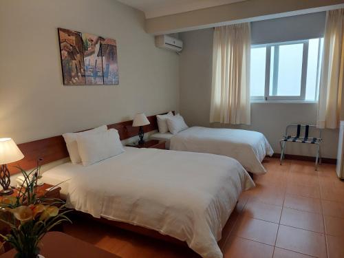 利马Lima Wasi Hotel Miraflores的酒店客房设有两张床和窗户。