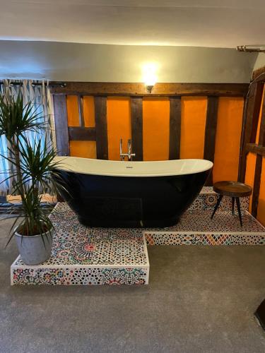 Little WilbrahamThe Hole In The Wall的浴缸,位于一个种植了盆栽植物的房间