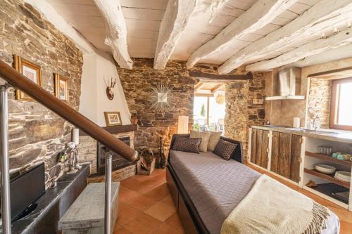 A PontenovaComplejo Rural Lar de Vies的一间设有床铺、电视和砖墙的房间
