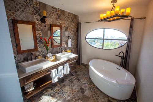 卡波圣卢卡斯恩坎塔达庄园别墅的一间带两个盥洗盆、浴缸和窗户的浴室