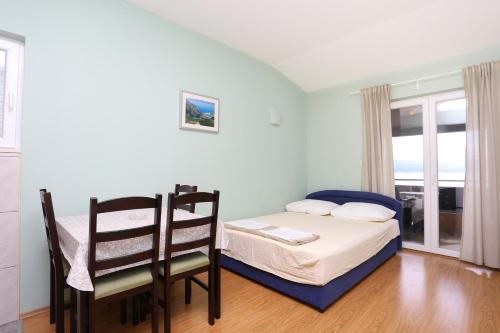 泰斯Apartments by the sea Nemira, Omis - 17039的卧室配有一张床和一张桌子及椅子
