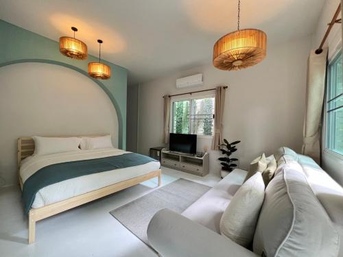 华欣Warm White Hua Hin House的一间卧室配有一张床、一张沙发和一台电视。