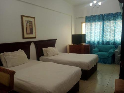拉斯阿尔卡麦Oasis Hotel Apartment的酒店客房,配有两张床和椅子