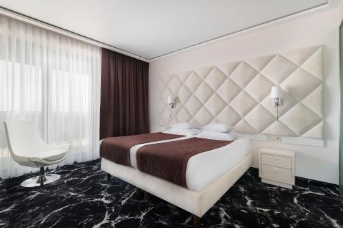 凯尔采奥德赛健康温泉俱乐部酒店的一间卧室配有一张大床和一张白色椅子