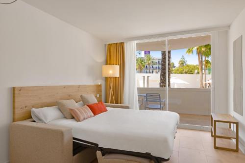 帕尔马诺瓦Palmanova Beach Apartments by TRH的一间卧室配有一张床和一张沙发,并设有一个阳台