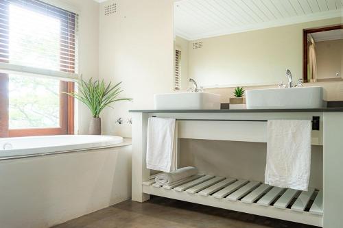 希尔顿Hilton Bush Lodge & Function Venue的浴室配有两个盥洗盆和浴缸。