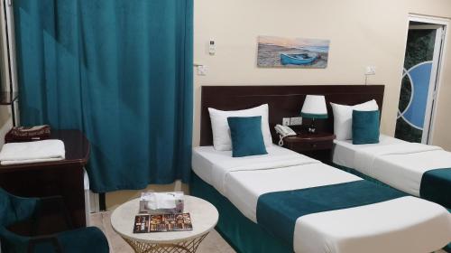 索哈尔Sadaf Hotel Apartments的酒店客房设有两张床和一张桌子。
