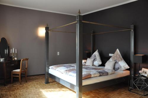 尼德根Ferienwohnung Rureifel的一间卧室配有一张天蓬床和书桌