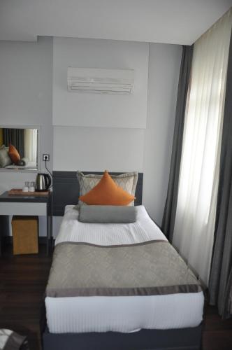 伊斯帕尔KOÇ OTEL ELİT TERMİNAL的一间卧室配有一张带橙色枕头的床