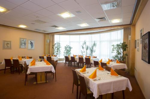 勒什Hotel Krek Superior的餐厅设有白色的桌椅和大窗户