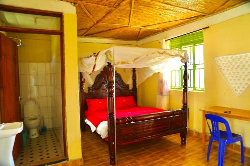 MpigiSina Village的一间卧室设有天蓬床和卫生间