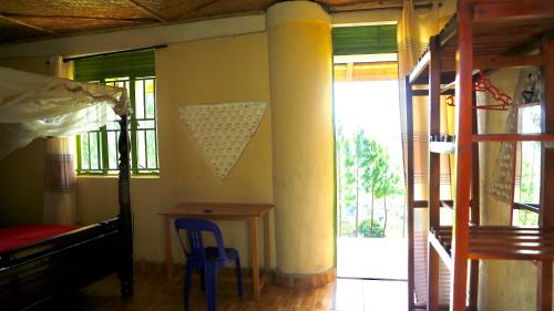 MpigiSina Village的一间卧室配有一张床、一张桌子和一个窗户。