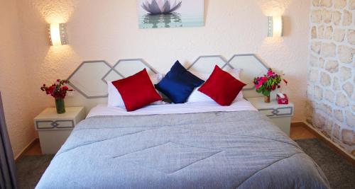西迪考乌奇Kaouki beach Apart'hotel的一间卧室配有一张带红色和蓝色枕头的床