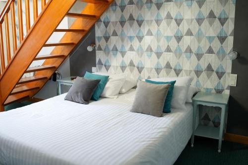 索姆河畔的圣瓦列里皮卡尔迪亚酒店的一间卧室配有带枕头的床和楼梯。