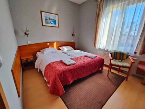 杰尔若纽夫德尔塔因酒店的一间卧室配有一张带红色毯子和椅子的床