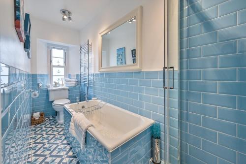 托基The Town House at Muntham- Luxury Holiday Home with Hot Tub的蓝色瓷砖浴室设有浴缸和卫生间