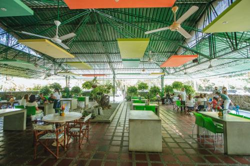 多拉代尔Makenke Hostel By Los Colores Ecoparque的一间设有桌椅的餐厅,有坐在桌子上的人