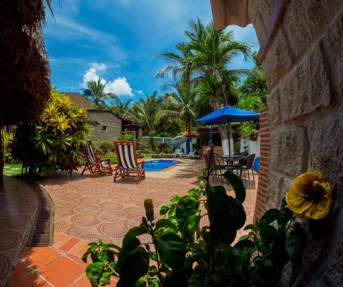 哥伦比亚港Portoazul Casa de Playa的庭院设有带椅子和蓝伞的游泳池。