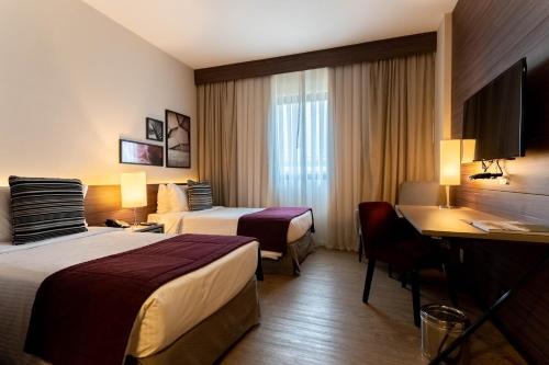 坎皮纳斯Royal Palm Tower Anhanguera的酒店客房配有两张床和一张书桌