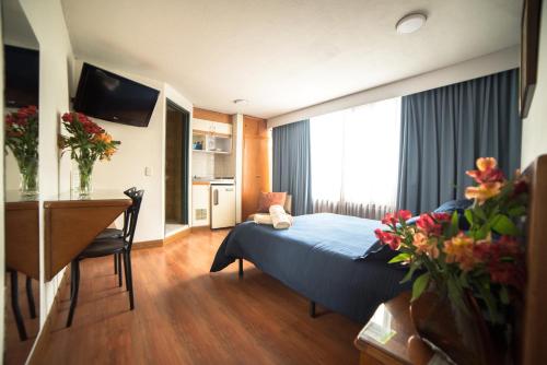 波哥大Apartamentos Galerías的酒店客房配有一张床铺、一张桌子和一张书桌。