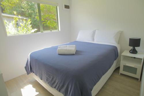 科罗曼德镇奥马鲁湾假日公园的一间卧室配有一张带蓝色毯子的床和窗户。