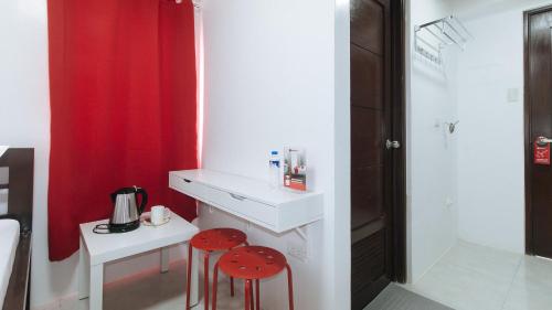 马尼拉RedDoorz near UST Sampaloc Manila的浴室设有2把凳子、水槽和红色窗帘
