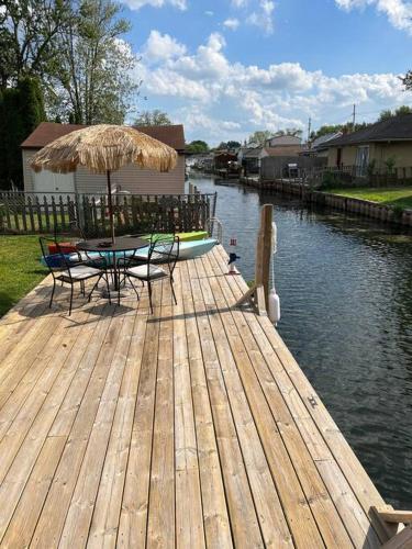 Waterfront Lake Saint Clair Lodge的木制甲板配有桌椅和遮阳伞