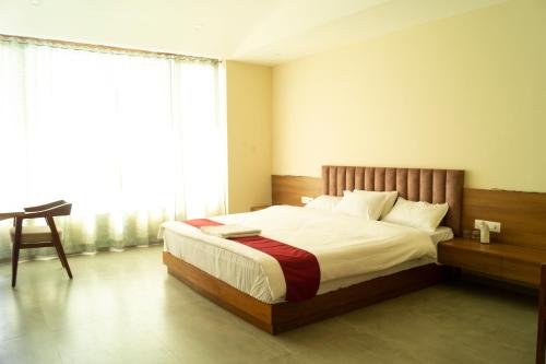 GolāghātChang's Garden & Resort的卧室配有床、椅子和窗户。