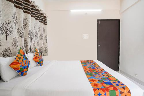 DāpuriFabHotel Vardhan House II的卧室配有白色的床和色彩缤纷的枕头