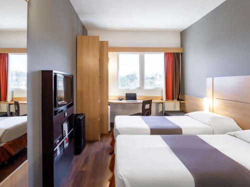 雅博蒂卡巴尔ibis Jaboticabal的酒店客房设有两张床和电视。