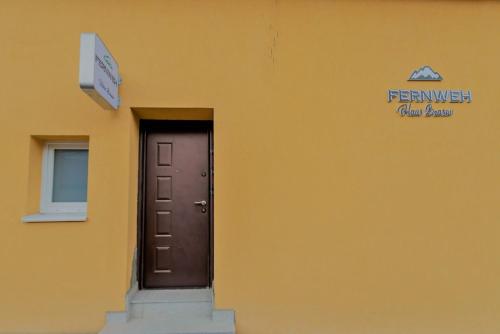 布拉索夫Fernweh Haus Brasov的黄色的建筑,有门和标志