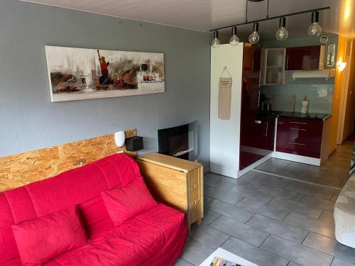 拉姆吉Studio pied de pistes avec place de parking privé extérieure LA MONGIE TOURMALET的一间带红色沙发的客厅和一间厨房