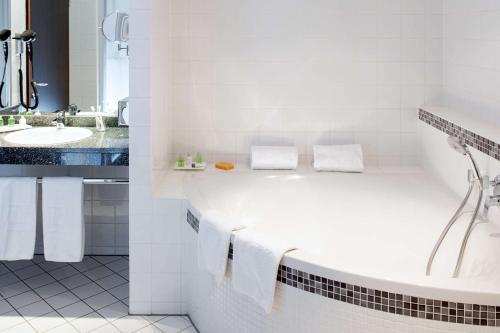 维也纳维也纳都市NH酒店的白色的浴室设有浴缸和水槽。