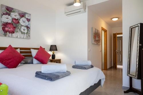 La GuirraIdeal for family holidays, near beach and golf- Casa James的一间卧室配有白色的床和红色和蓝色枕头