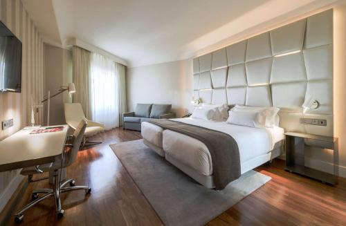 马德里马德里科隆NH系列酒店的酒店客房设有一张大床和一张书桌。