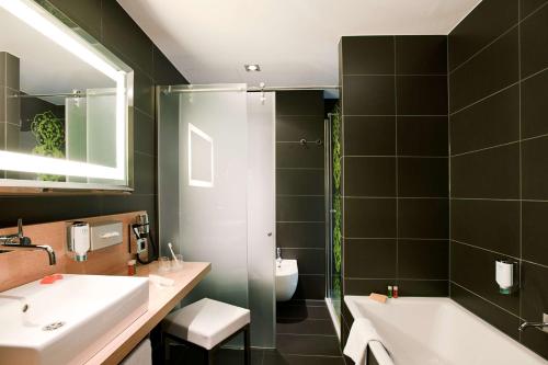 美因河畔法兰克福NH法兰克福展会酒店的一间带水槽、浴缸和卫生间的浴室