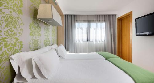 雷阿尔城NH皇城酒店的卧室配有白色的床和窗户。