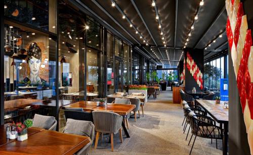伊斯坦布尔G Tower Furnished Apartment Rentals的餐厅设有木桌、椅子和许多窗户