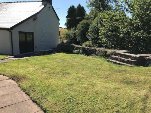 布雷肯Cobblers Cottage in Brecon Beacons的一座带草地庭院的白色小房子