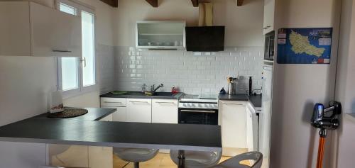 索宗Maison entre Terre et Mer avec Jacuzzi的厨房配有白色橱柜和黑色台面